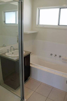 Bathroom contains shower and bath to clean up after a day at the beach.